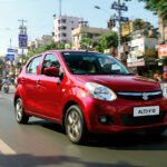 Red Maruti Suzuki Alto K10 driving on Indian roads with modern city background, symbolizing power, mileage, and reliability.